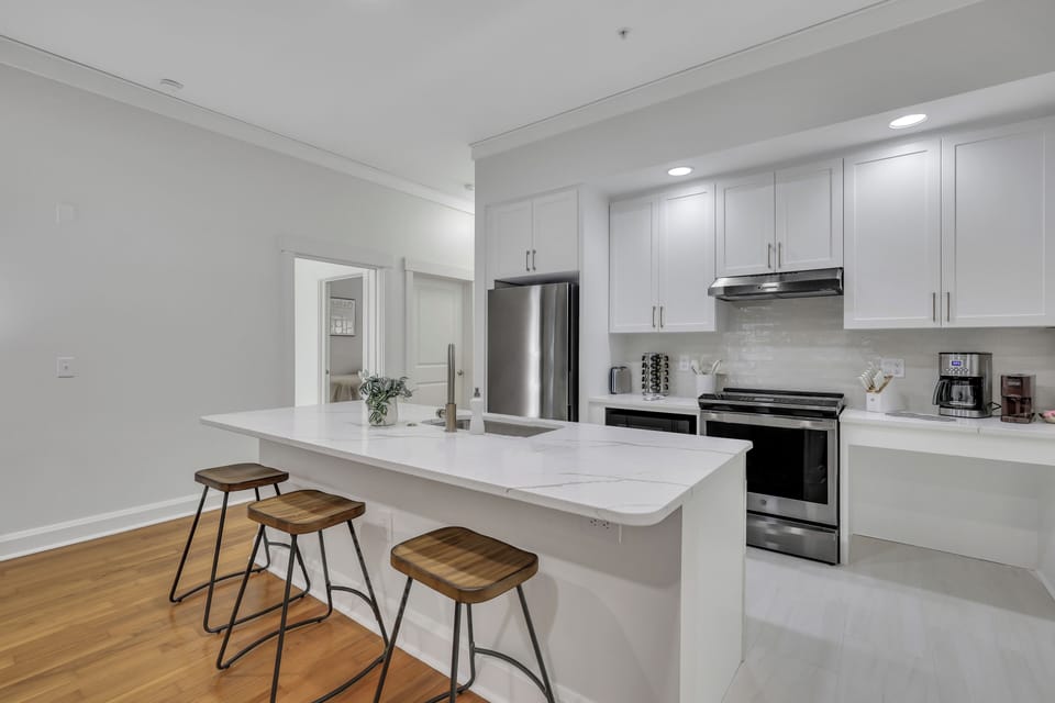 Contemporary kitchen with island seating, stainless steel appliances, and white cabinetry.