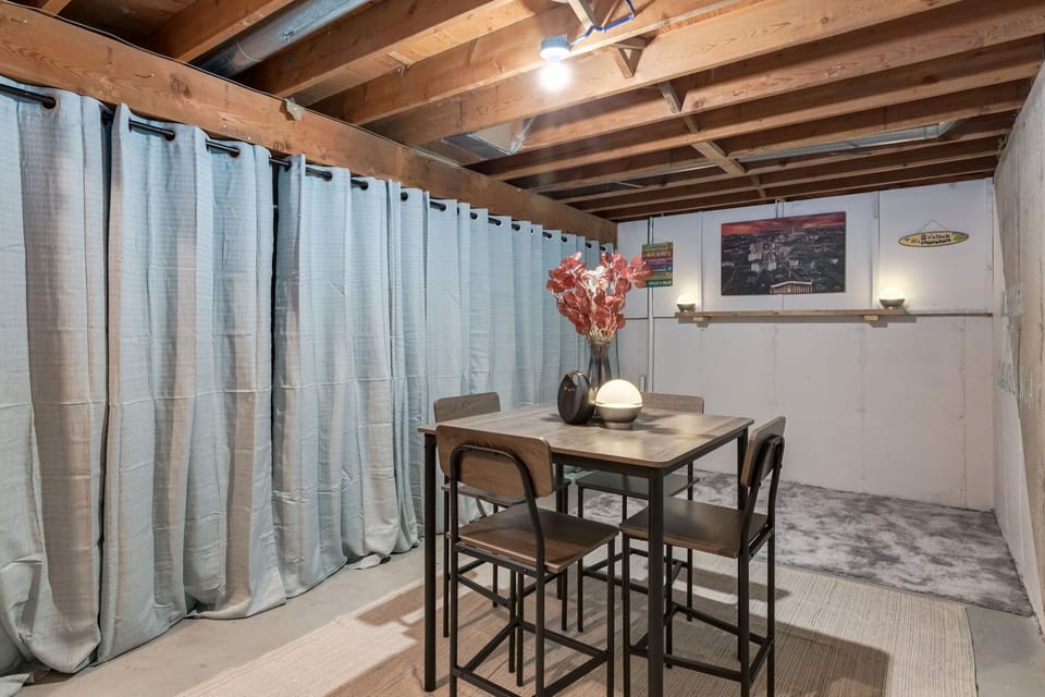 Game room setup with exposed beams and soft draped dividers for a cozy, intimate vibe
The café-style table and overhead lighting create a warm gathering spot for games, late-night snacks, or relaxed conversation.
