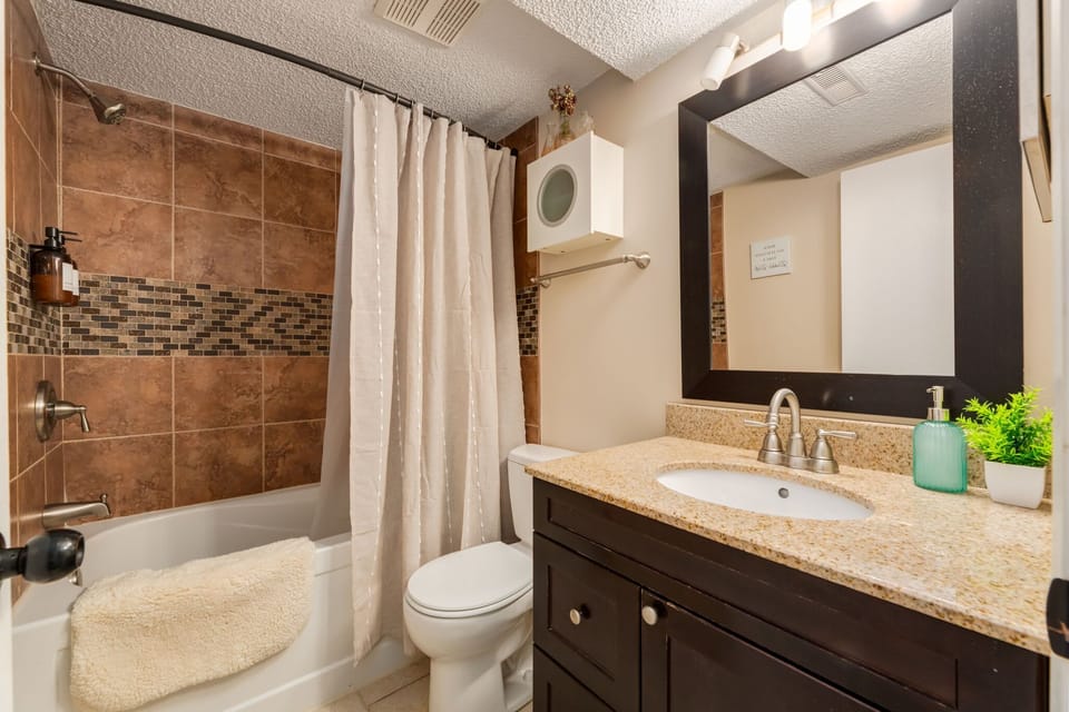 Full bathroom with a stone-trimmed tub surround, generous vanity, and thoughtful amenities
Warm tones and well-placed décor pieces create a spa-like feel.