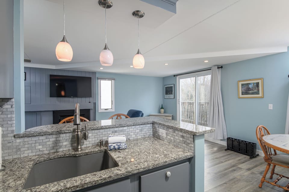 Cook and entertain with ease in this modern open-concept kitchen featuring granite countertops, pendant lighting, and a cozy living area with fireplace perfect for relaxing.