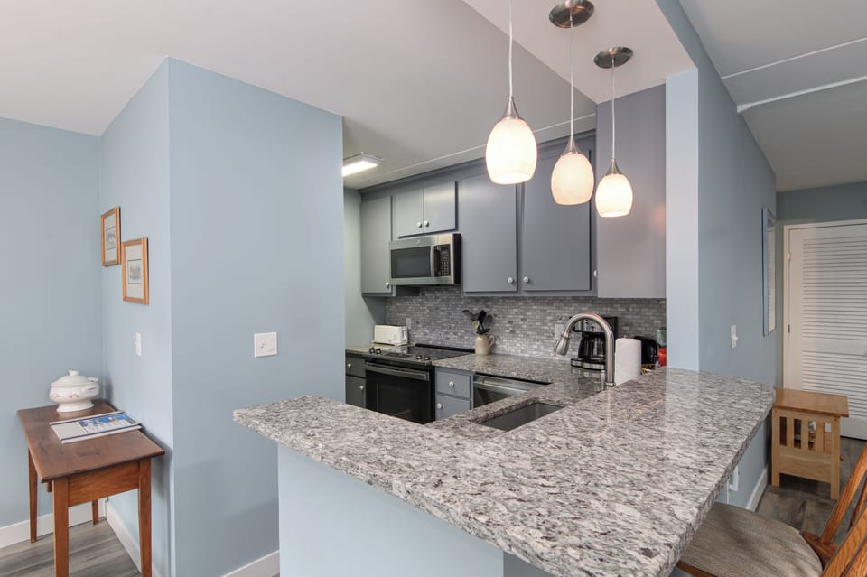 Your fully equipped kitchen features granite countertops, modern appliances, and elegant pendant lighting, perfect for preparing meals during your stay.