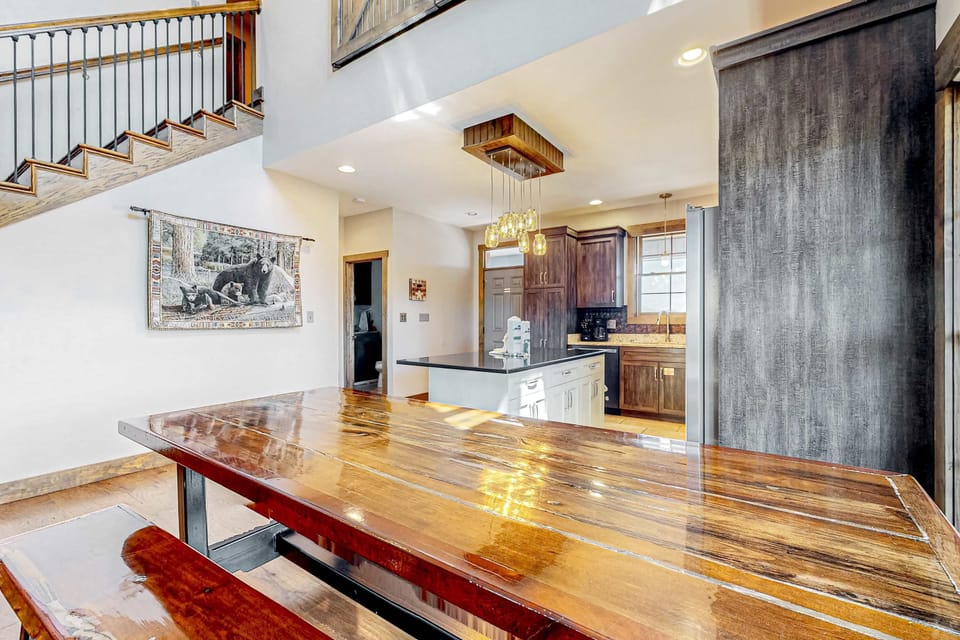 Large dining table in a bright open-concept cabin with modern farmhouse kitchen and loft-style layout. Perfect for family meals, group dinners, and unforgettable vacation stays.