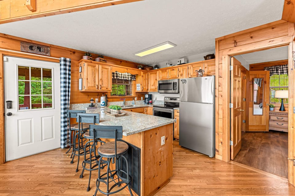 Dining area and kitchen with island seating, wood cabinetry, and modern appliances. Designed for cooking, gathering, and entertaining.