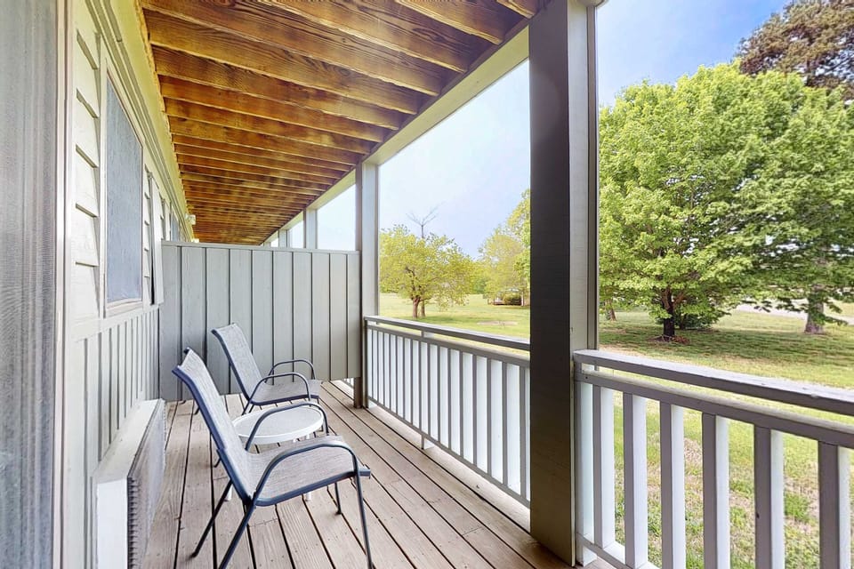 Private covered balcony with chairs and peaceful green views. Relax with coffee, fresh air, and sunsets; great outdoor space for couples, golf trips, and quiet weekend getaways.
