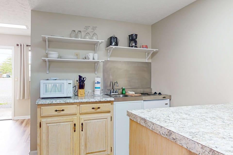 Compact kitchenette with microwave, mini-fridge, coffee maker, sink & essentials. Easy meals for extended stay, work trip, or weekend getaway; convenient studio-style amenities and counter space.