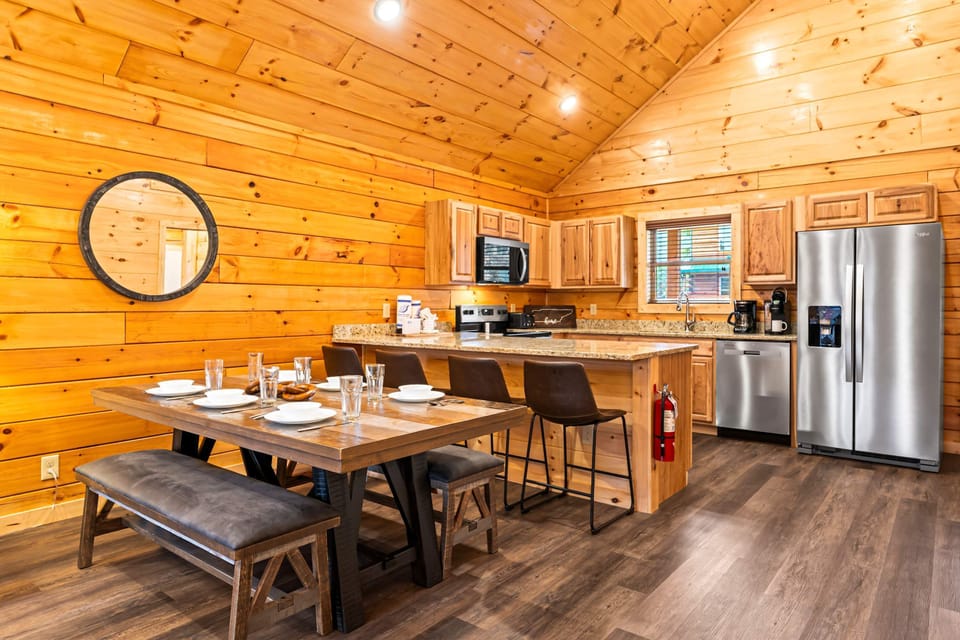 Spacious kitchen and dining area with large table, island seating, and modern cabin finishes. Ideal for group trips, family vacations, and cooking together in your mountain cabin.