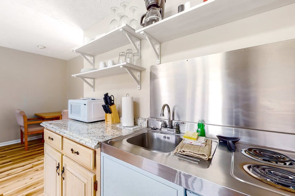 Stocked kitchenette with cooktop, sink, microwave, coffee setup, dishes & glassware. Perfect for extended stays and easy meals. Studio suite with mini kitchen, convenient amenities, and quick dining.