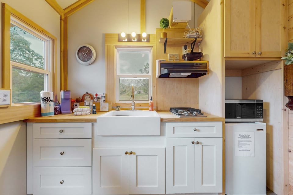 Modern compact kitchen with farmhouse sink and cooktop. Perfect for romantic weekends, outdoor adventures, and peaceful stays.