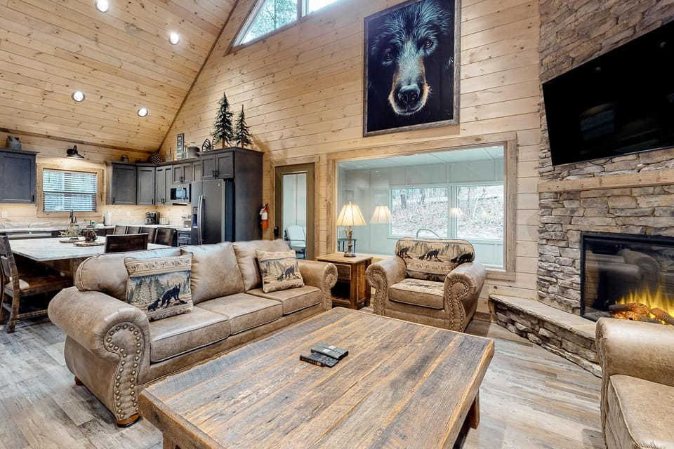 Open-concept cabin living area with fireplace, plush seating, vaulted ceilings, and mountain décor. Designed for comfort and gathering in a luxury Smoky Mountains cabin.