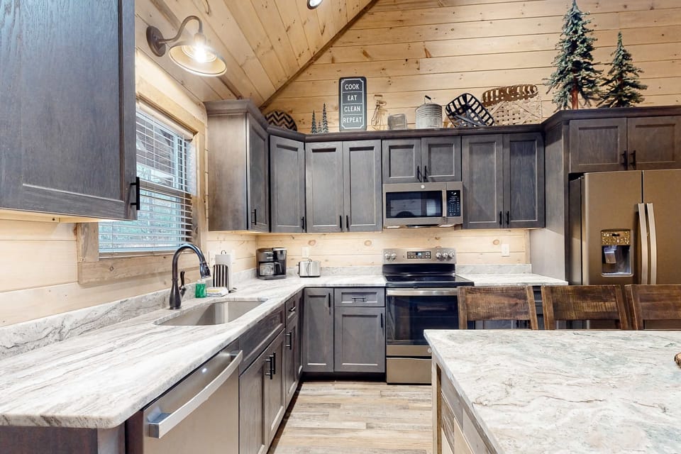 Fully equipped cabin kitchen with stainless steel appliances, granite countertops, island seating, and ample storage. Ideal for cooking during your Smoky Mountains vacation.