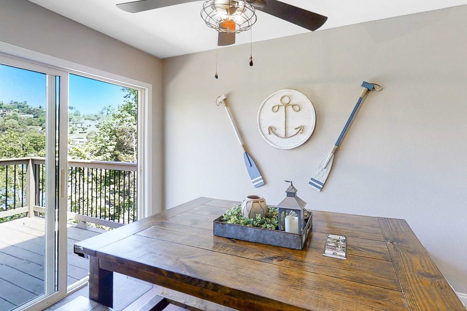 Dining space with large table and sliding doors to the deck. Ideal for meals and gatherings; easy indoor/outdoor flow, lake views, and bright natural light for family vacations and group stays.