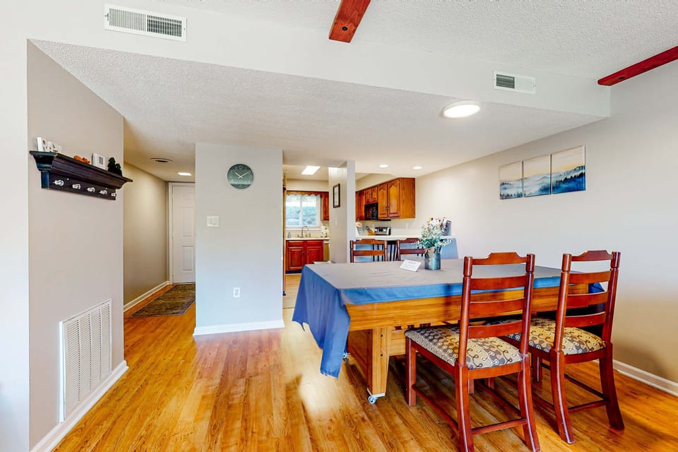 Dining table + open kitchen flow. Perfect combo for gatherings, meals, and work space; comfortable condo getaway with plenty of seating and bright lighting.