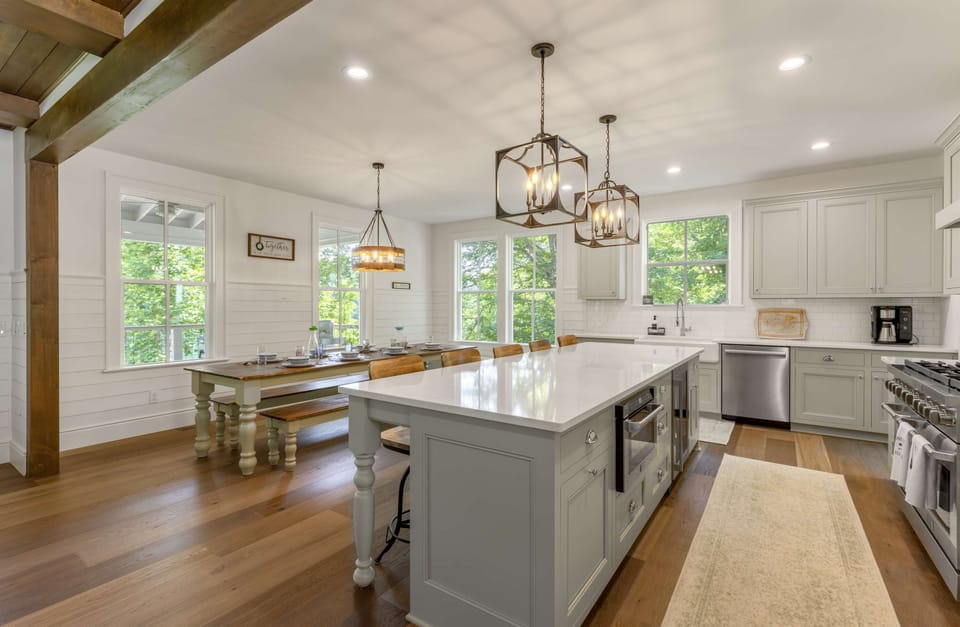 Spacious gourmet kitchen with oversized quartz island, bar seating, and farmhouse dining table. 