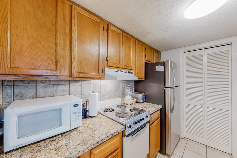 Clean, functional kitchen with stove, microwave, refrigerator, ample cabinets, and counter space. Everything needed for home-cooked meals.