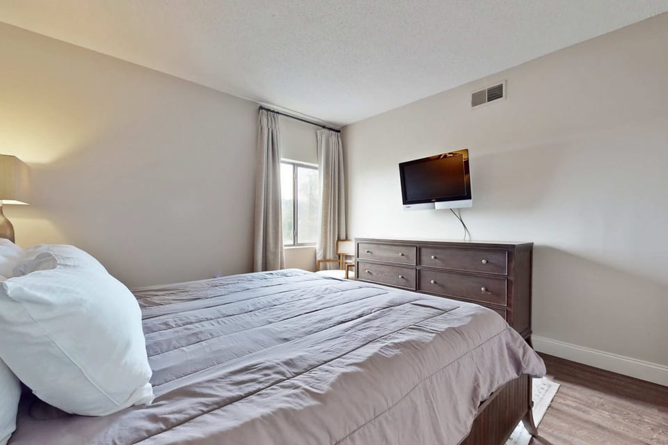 Relax in style with a plush bed, airy windows, and sleek decor. Perfect rest awaits!