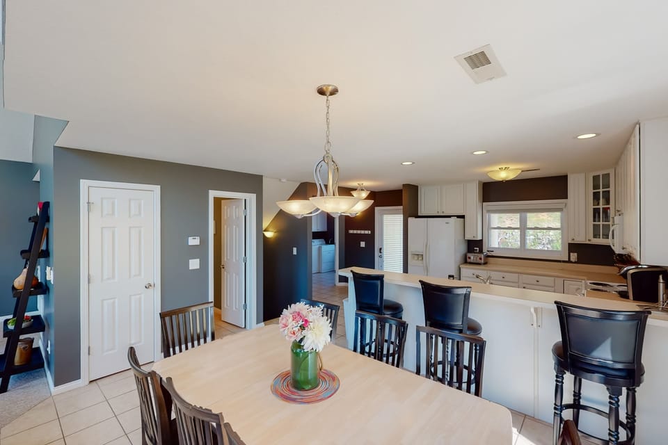 Open dining area with large table and breakfast bar seating. Ideal for shared meals, family gatherings, and group entertaining.