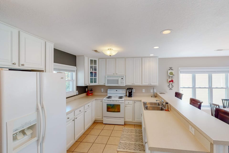 Bright, fully equipped kitchen with white cabinetry, full-size appliances, and ample counter space. Perfect for cooking family meals and lake-day snacks.
