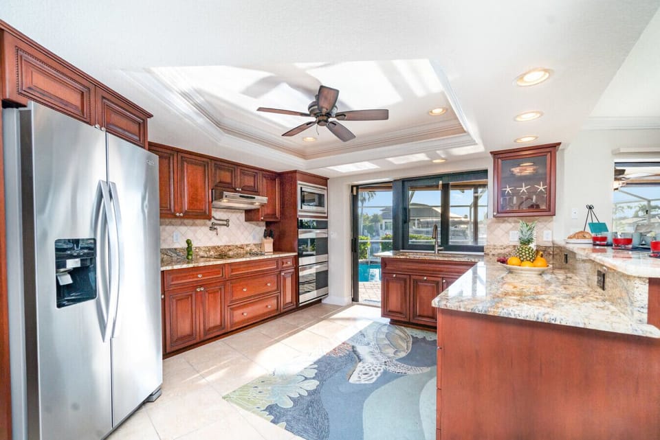 Chef-inspired gourmet kitchen with granite countertops, stainless steel appliances, and direct access to the pool — perfect for entertaining.