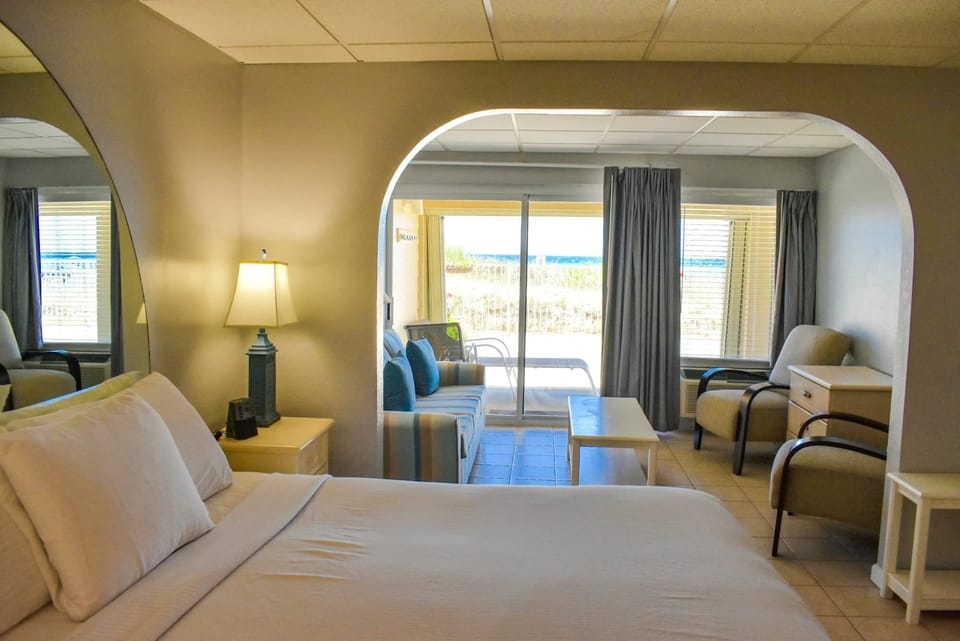 Inside the studio, natural light floods the space, highlighting the inviting sleeping area and cozy seating that overlooks the tranquil beach, creating a perfect retreat for relaxation.