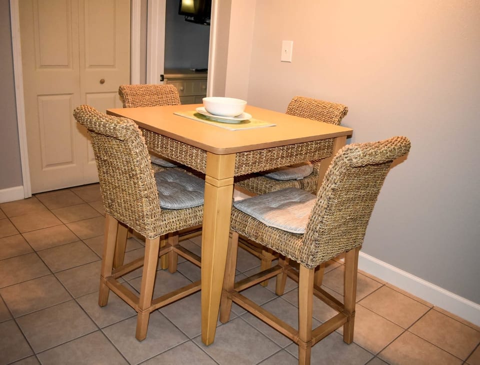 A cozy dining area featuring a wooden table surrounded by four wicker-style chairs, perfect for casual meals.