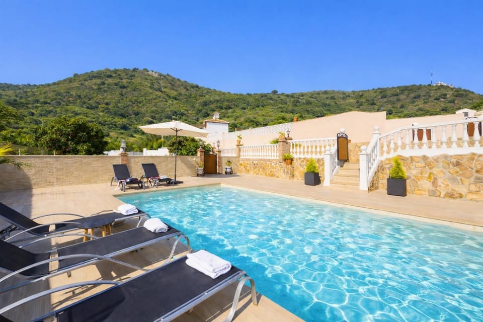 A ground-level perspective from the edge of the water, showcasing the full length of the shimmering swimming pool and the multi-tiered layout of the pool deck.