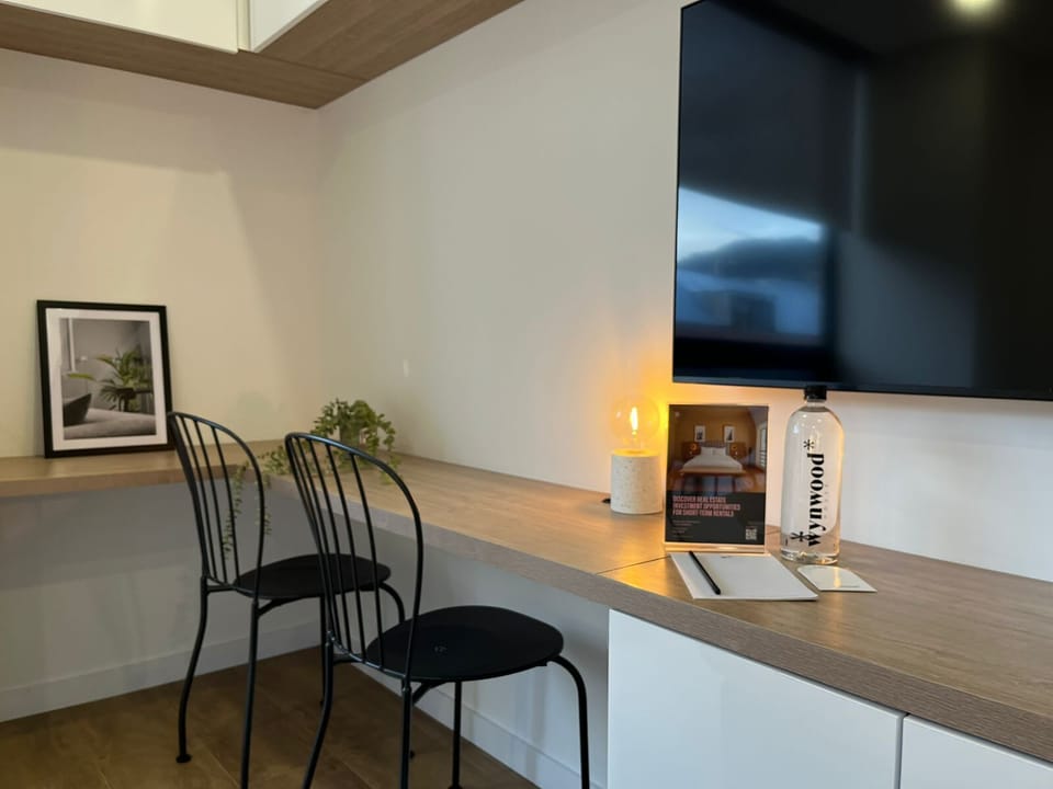 A compact workspace with a clean desk setup and decorative elements beneath the wall-mounted TV