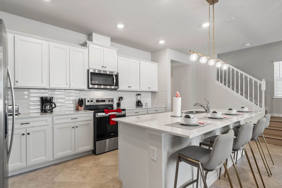 Sleek white kitchen meets open-concept living-gather at the island for 4 while dinner sizzles on the stainless range and the modern backsplash shines.