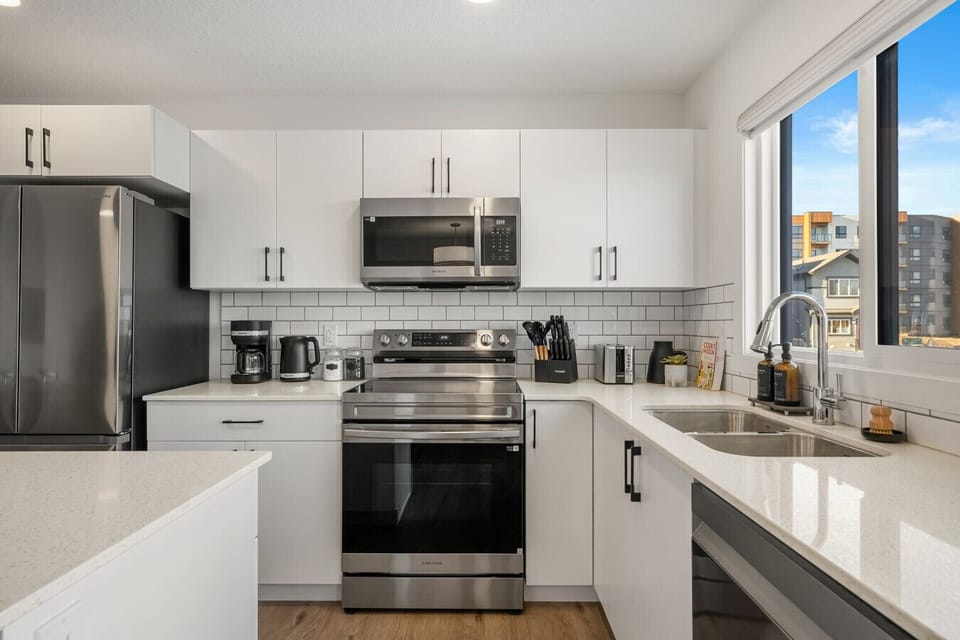 Well-equipped kitchen with stainless steel appliances and white cabinetry throughout