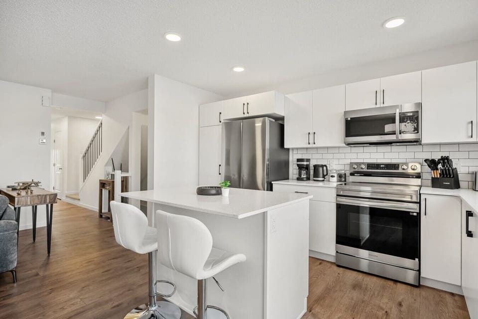 Well-equipped kitchen with white cabinets, stainless steel appliances, and breakfast island