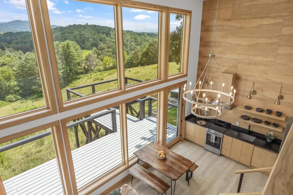 A chandelier is installed for even overhead lighting, complemented by a large glass window that enhances the room with natural daylight and open views.