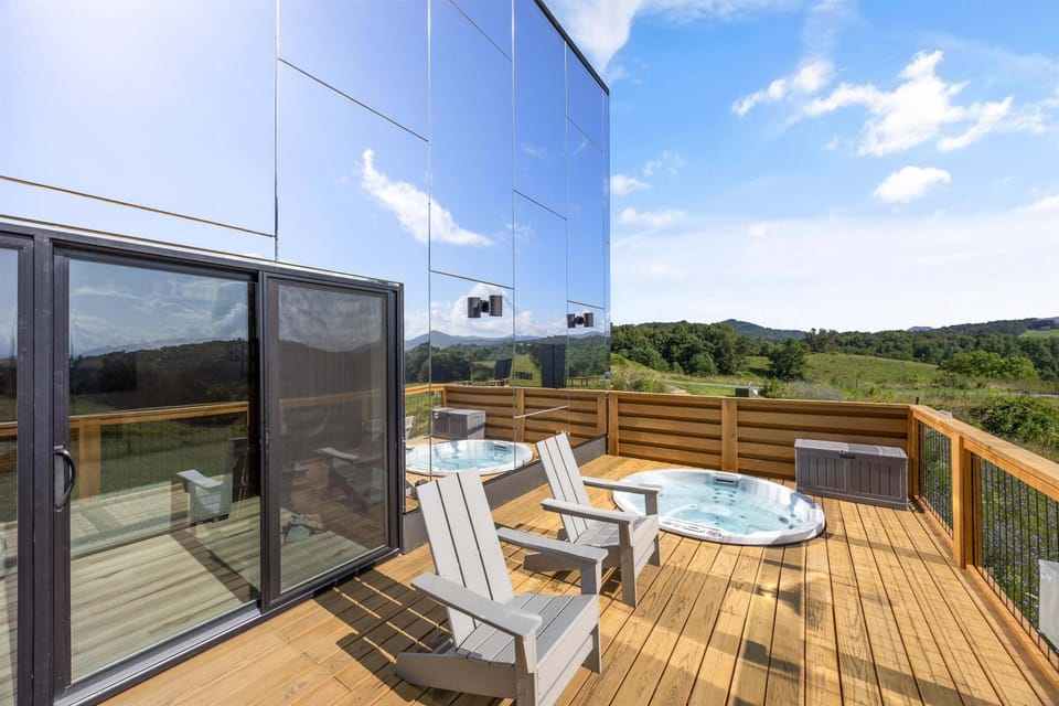 Spacious outdoor deck featuring a hot tub, lounge chairs, and stunning panoramic mountain scenery.