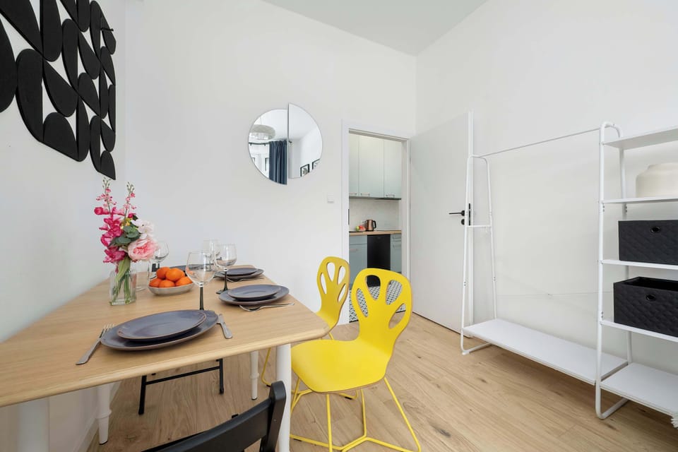 Dining table setup with flowers, fruit, and yellow chairs adding vibrant contrast.