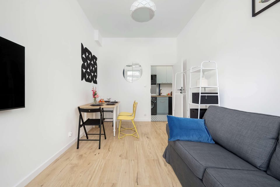 Dining and bedroom with a grey sofa, wooden floor, and minimalist décor.