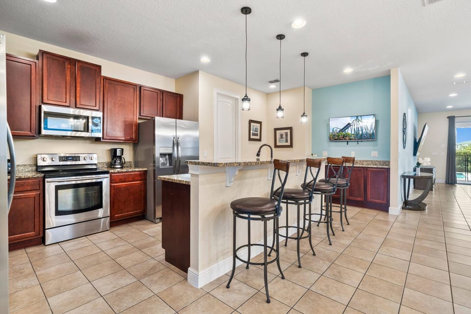 Bright kitchen w/ breakfast bar seating & stainless steel appliances