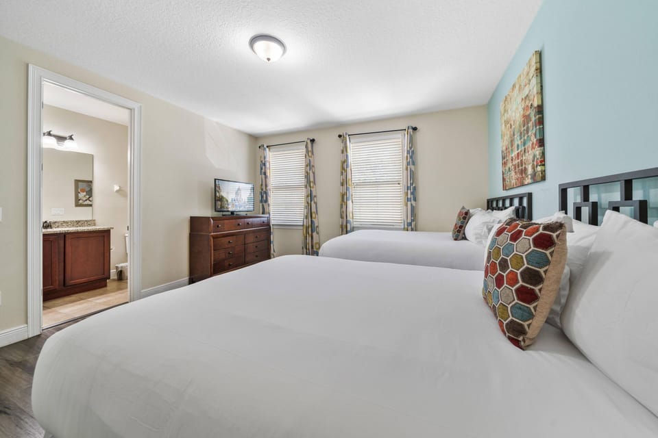 Spacious bedroom w/ dual beds, soft tones, and ensuite access for added convenience