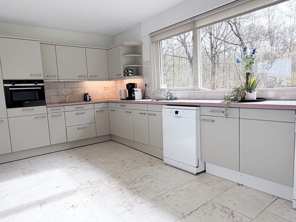 Modern Tilburg kitchen with stove, oven, fridge, coffee maker, and complete cookware.