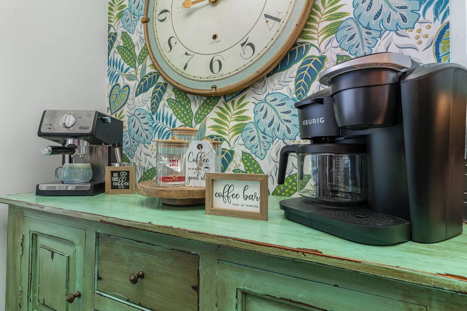 Start your mornings right at your personal coffee bar with espresso machine and Keurig, beautifully styled against tropical wallpaper.