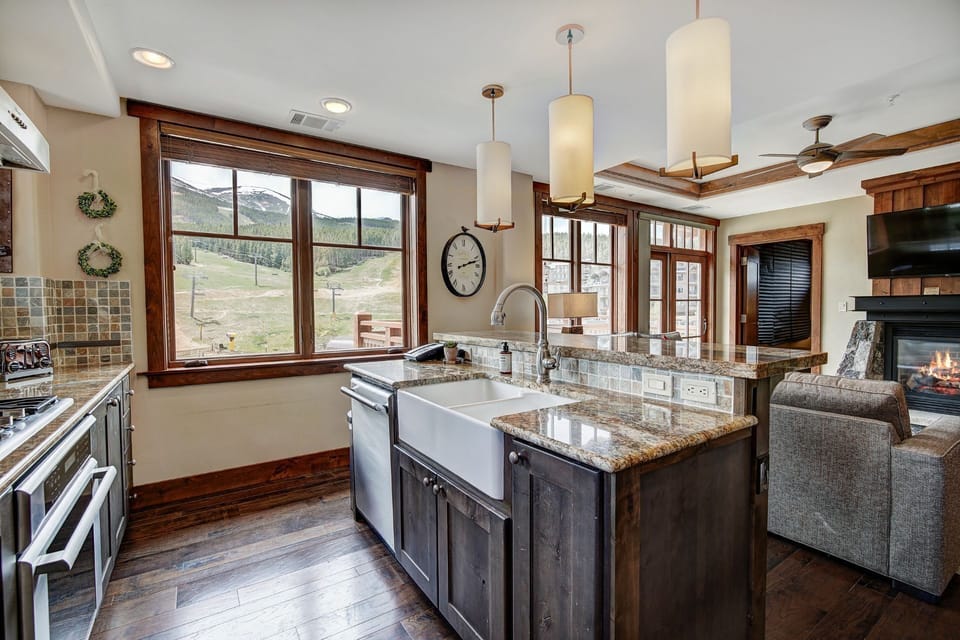 Bright open kitchen and living space with a breakfast island and scenic views — perfect for entertaining or casual dining.