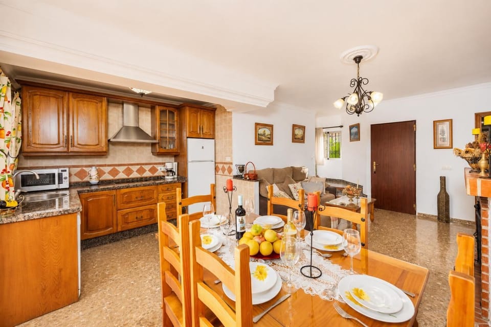 Open-plan living room with sofa, dining area, kitchen, ornamental fireplace, A/C, WiFi internet, and satellite TV