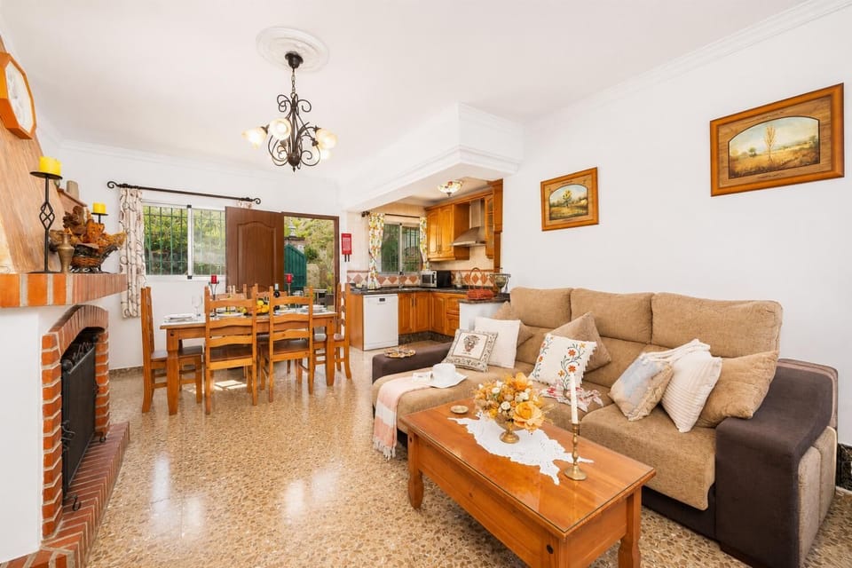 Open-plan living room with sofa, dining area, kitchen, ornamental fireplace, A/C, WiFi internet, and satellite TV
