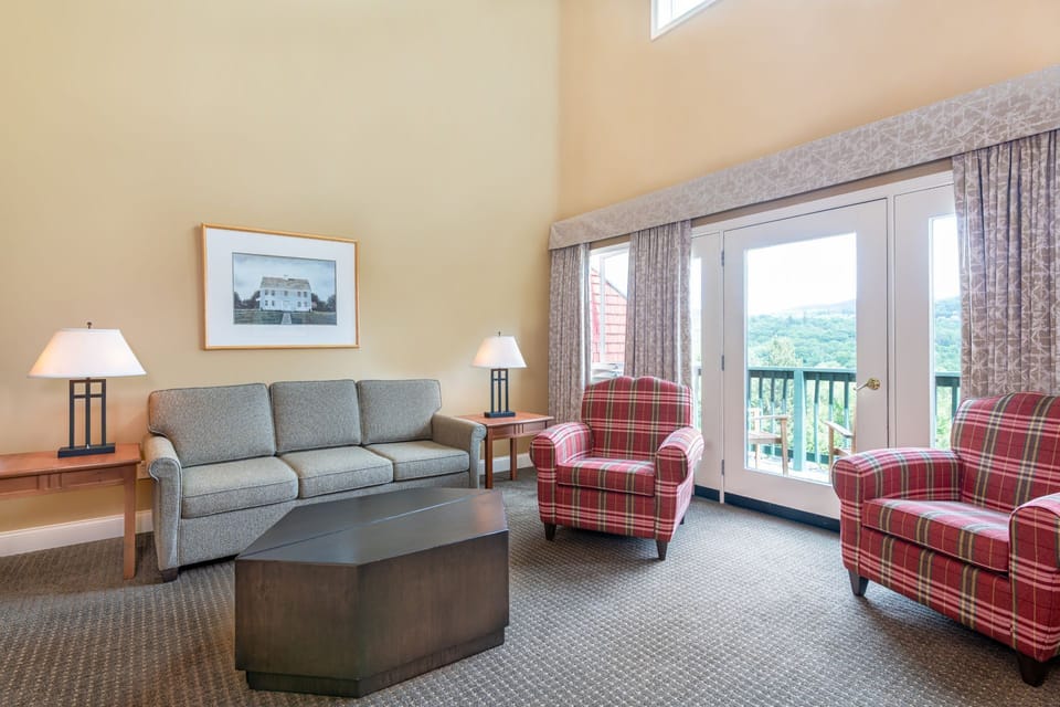 Spacious living room with vaulted ceilings, comfortable furnishings, and large windows that open to scenic mountain views.