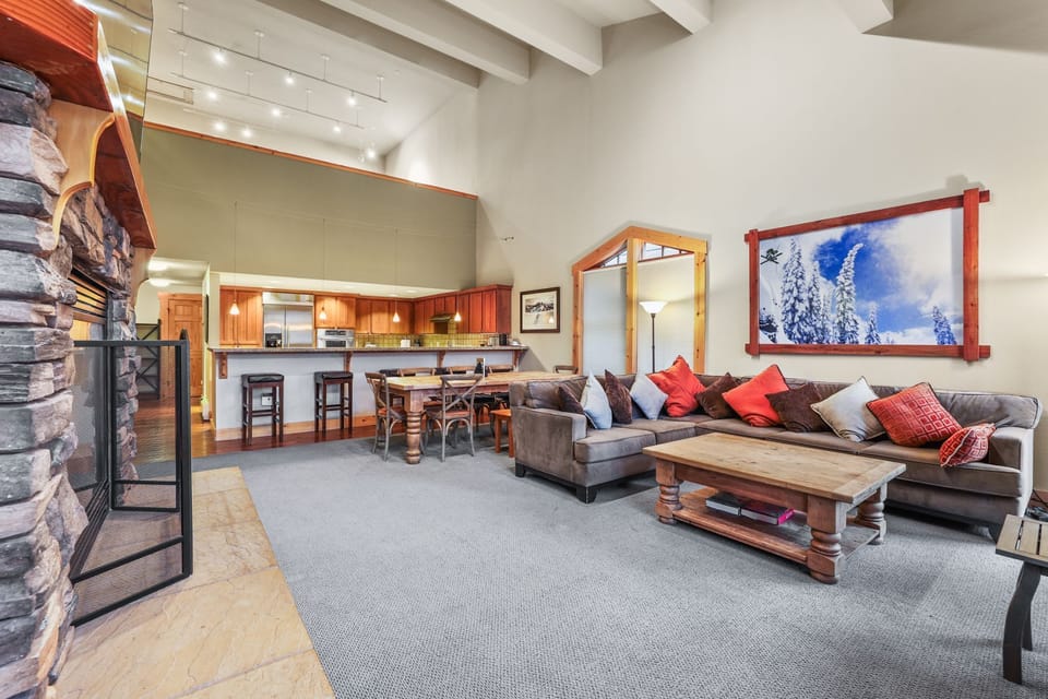 Step inside this enchanting sanctuary where alpine warmth meets modern elegance. The spacious living area invites you to unwind, adorned with a plush sofa and vibrant accent pillows that echo the beauty of the surrounding mountains.