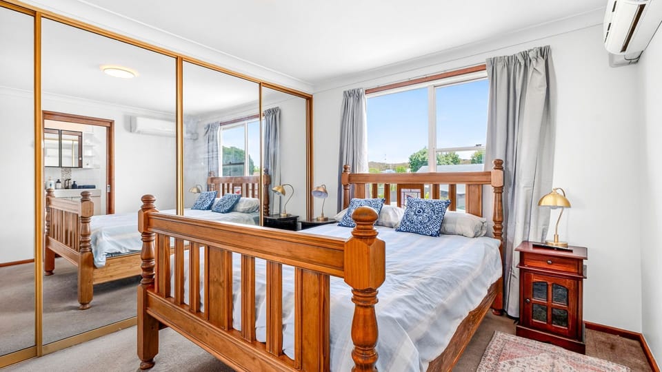 Bright master bedroom with large windows and warm timber tones