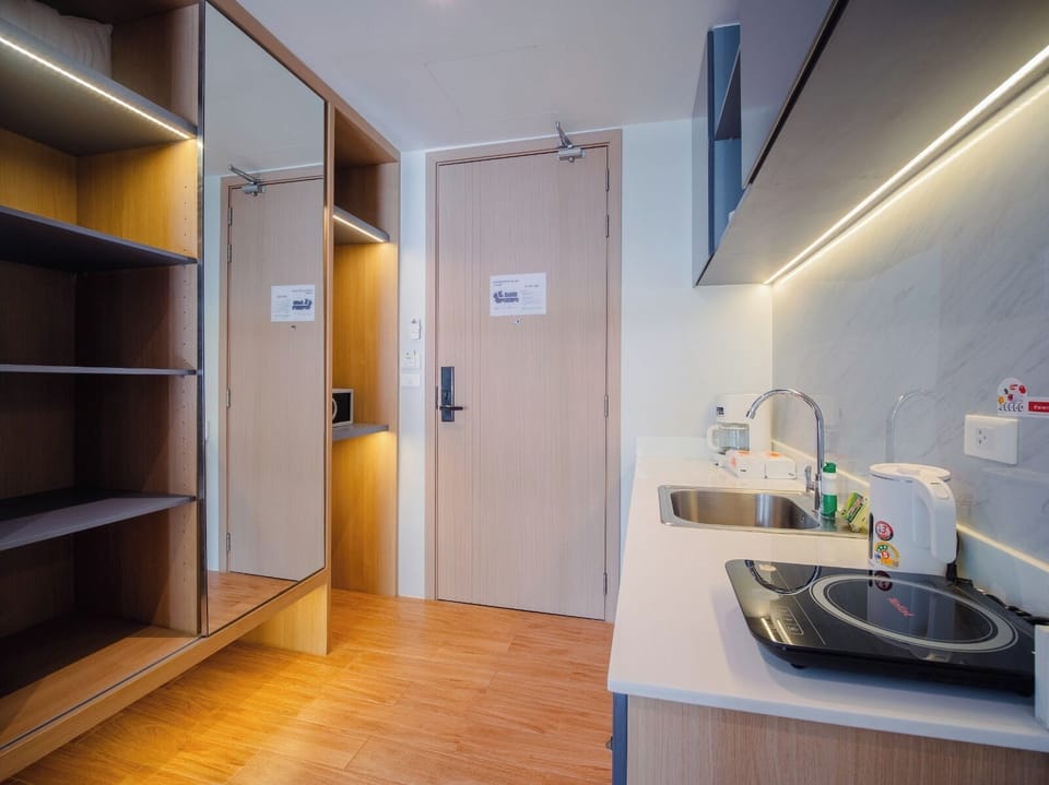 Compact entry area with built-in wooden storage, a small kitchenette with sink, and modern minimalist design.