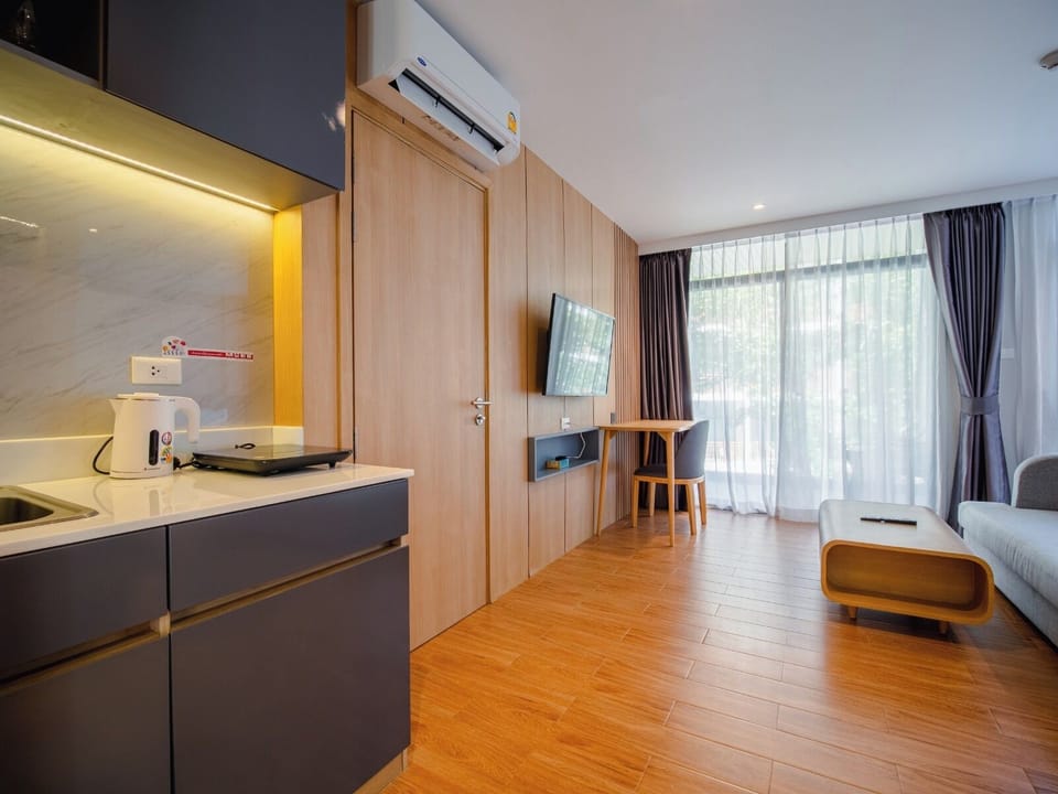 Bright studio interior featuring a kitchenette, workspace, and floor-to-ceiling windows that bring in natural light.