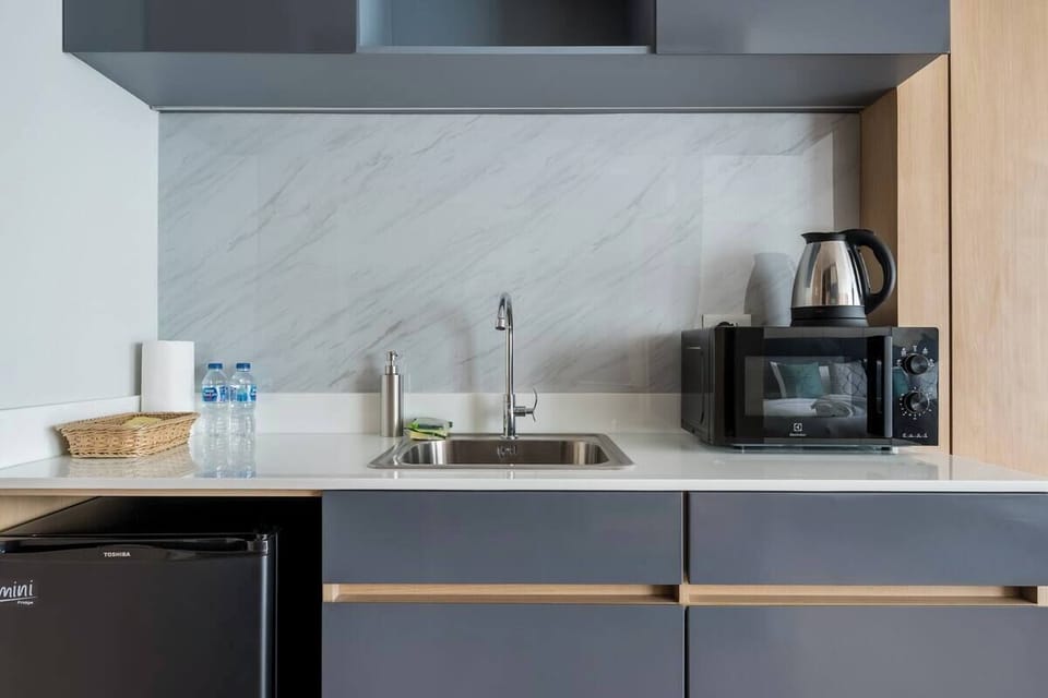 Compact kitchenette fully equipped with sink, microwave, kettle and basic utensils for light meal preparation.