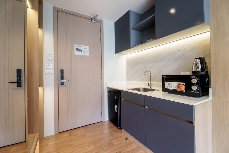Compact kitchenette equipped with microwave, kettle, sink and basic essentials for light meal preparation.