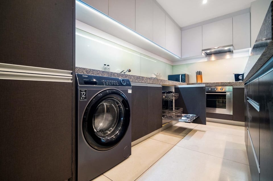 Modern kitchen featuring a washing machine, oven, stovetop, and sleek cabinetry for convenient self-catering.