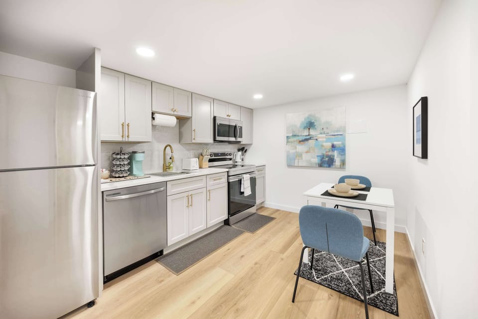 A sleek and fully equipped kitchen with stainless steel appliances, modern cabinetry, and a cozy dining nook. Ideal for home-cooked meals or enjoying morning coffee in a beautifully designed space.
