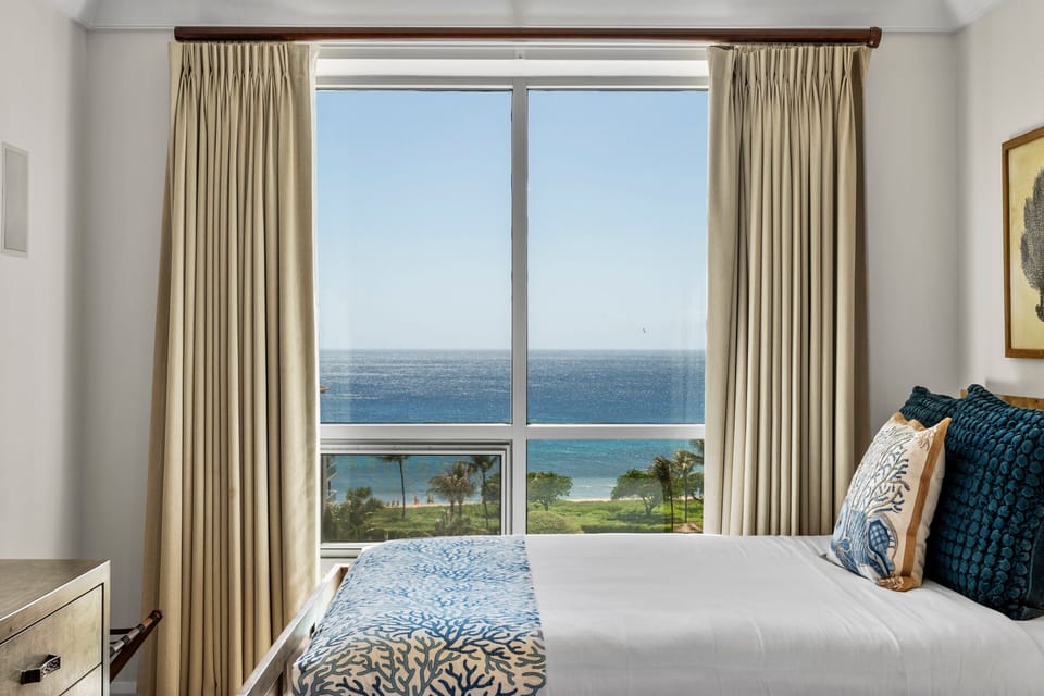 Enjoy coastal breezes from this room with large window and soft beige curtains.